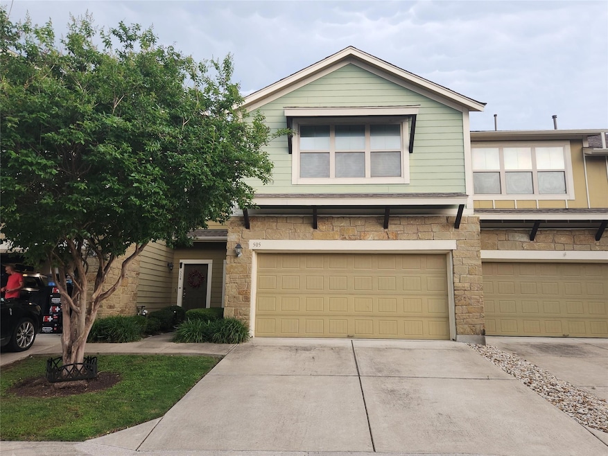 View of property with a garage, driveway, and sto