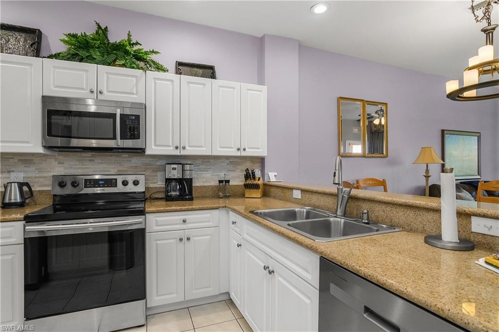 Kitchen with backsplash, appliances with stainless steel finishes, a sink, and light tile patterned floors