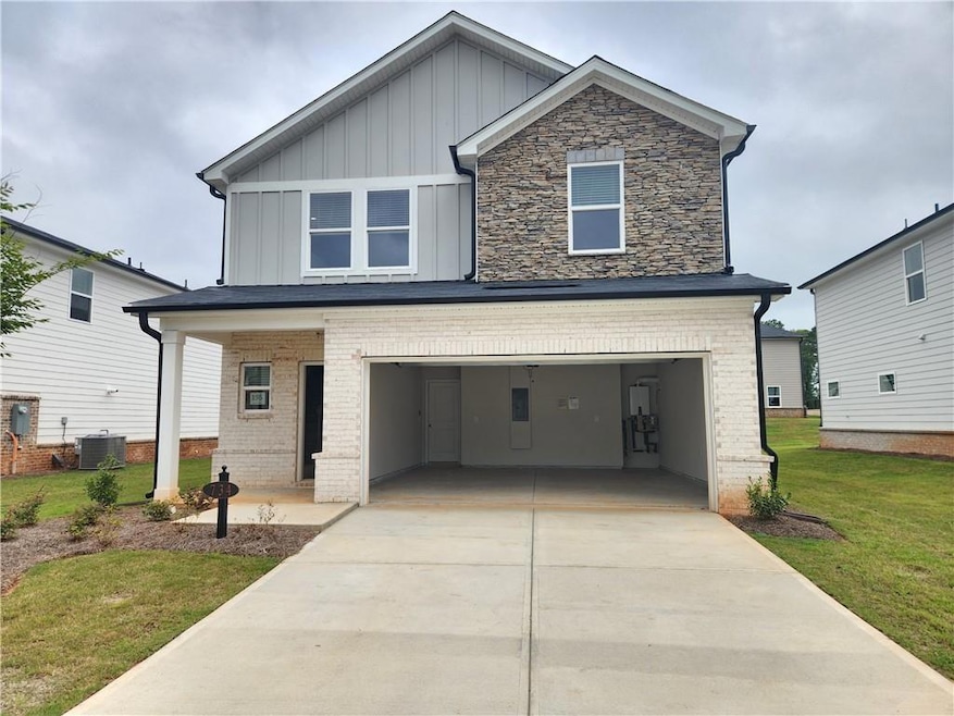 Craftsman inspired home featuring a front yard, a garage, board and batten siding, and concrete driveway