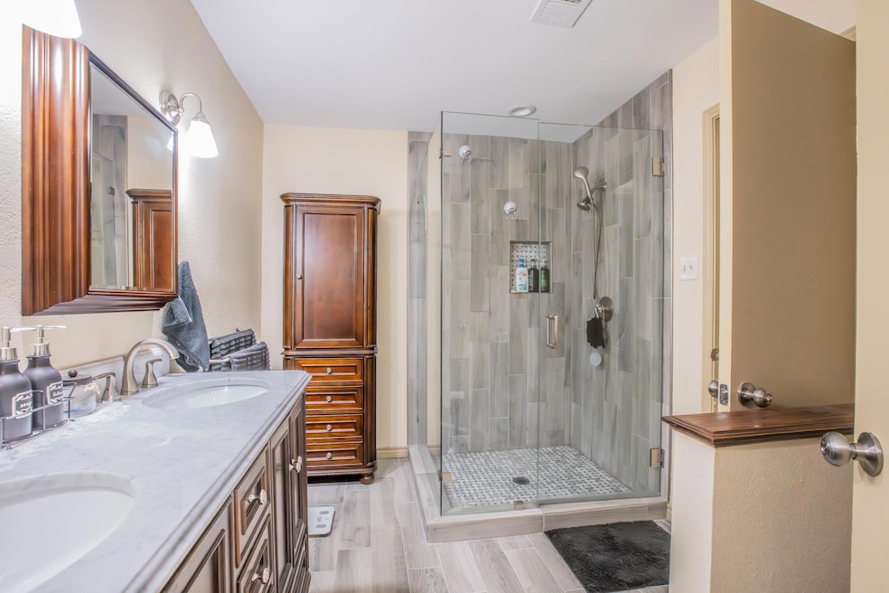Bathroom with double vanity, a glass stall shower,