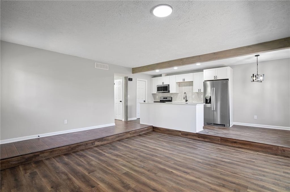Unfurnished living room featuring a textured ceiling, dark wood-style floors, a chandelier, and recessed lighting