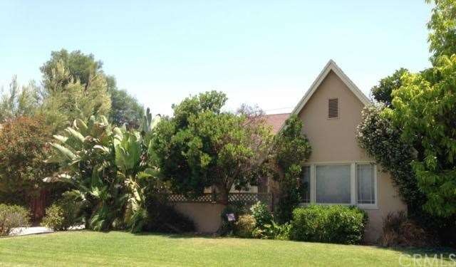 FRONT OF VINTAGE, TUDOR STYLE HOME WITH LUSH PLANT