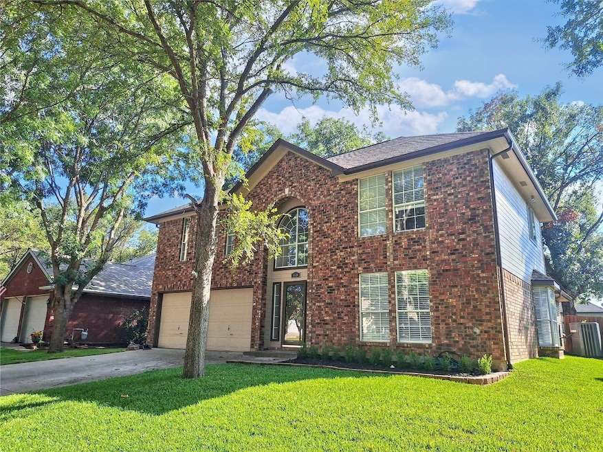 View of front facade with a front lawn, brick siding, driveway, and an attached garage