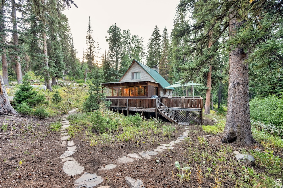 Front view of house with stairs, a deck, and a wooded view