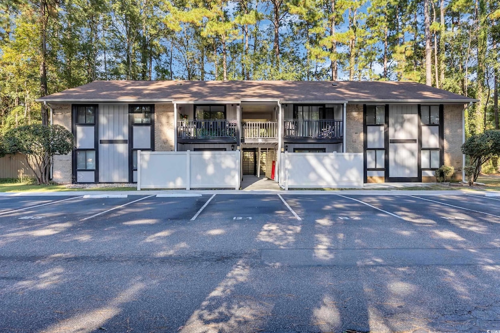 View of front of house featuring a shingled roof, uncovered parking, and brick siding