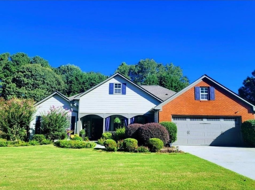 Traditional-style house featuring a front lawn, a garage, driveway, brick siding, and covered porch