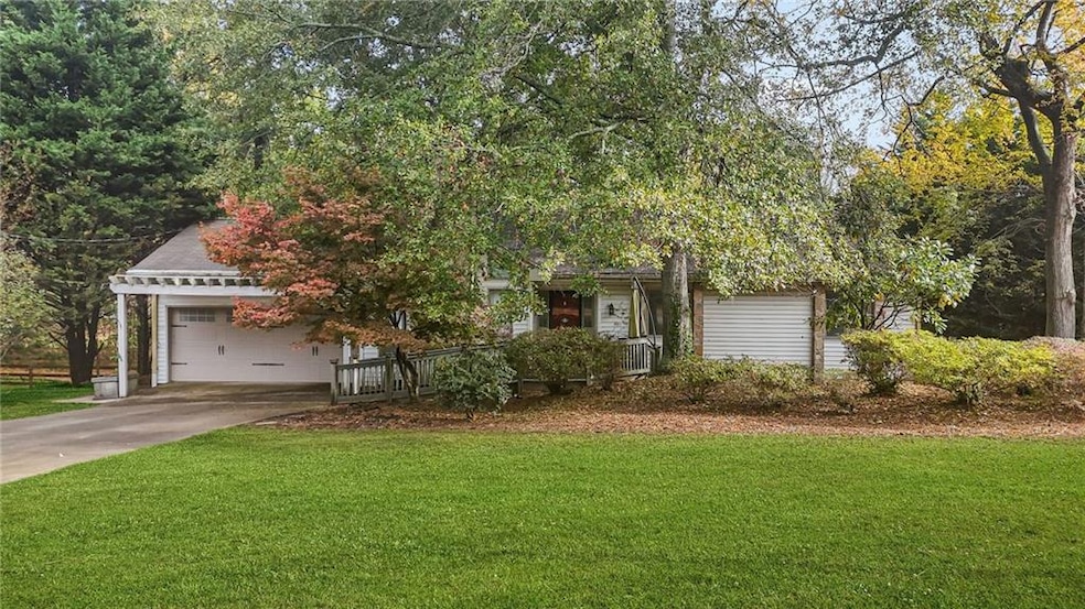 View of property hidden behind natural elements with a front lawn, concrete driveway, roof with shingles, and a garage