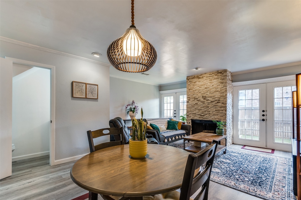 Dining room featuring french doors, ornamental molding, wood finished floors, and a fireplace