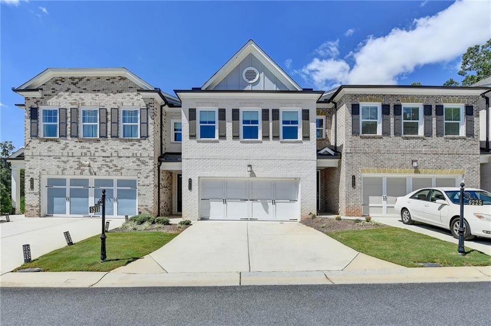 View of front facade featuring driveway, brick siding, and an attached garage