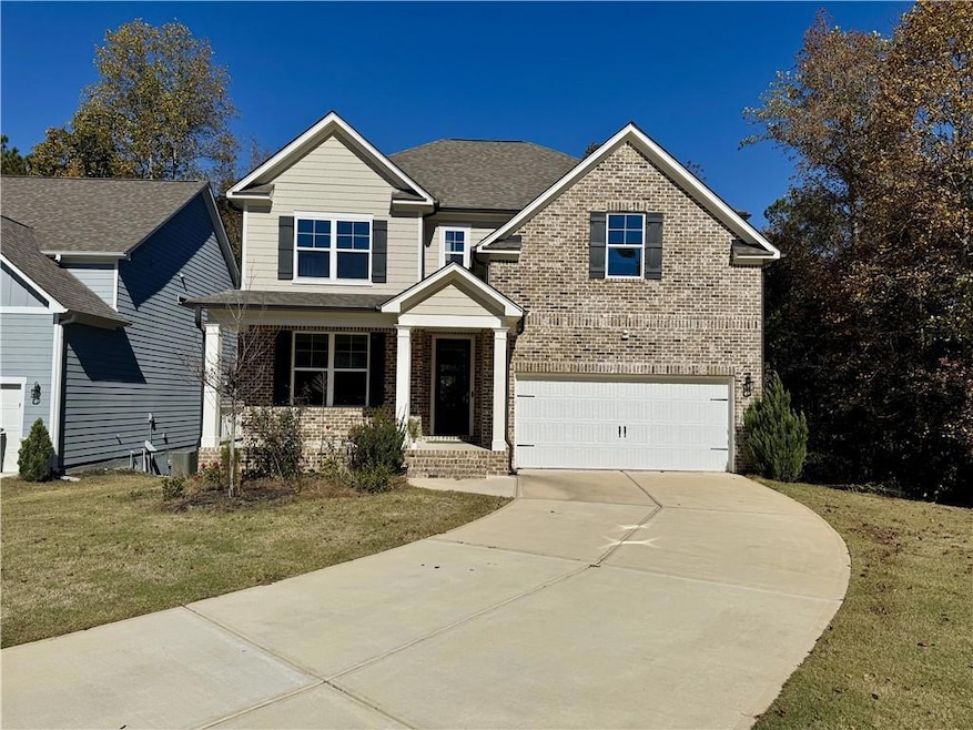 View of front of home featuring brick siding, a porch, a front lawn, and concrete driveway