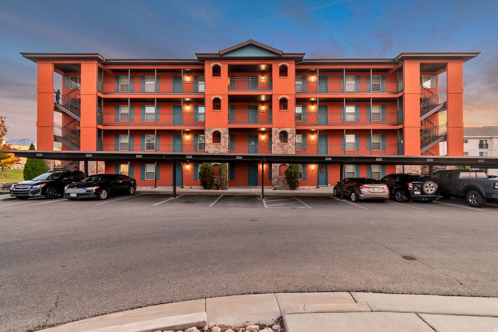 Property at dusk featuring covered parking and a view of apartment building / complex