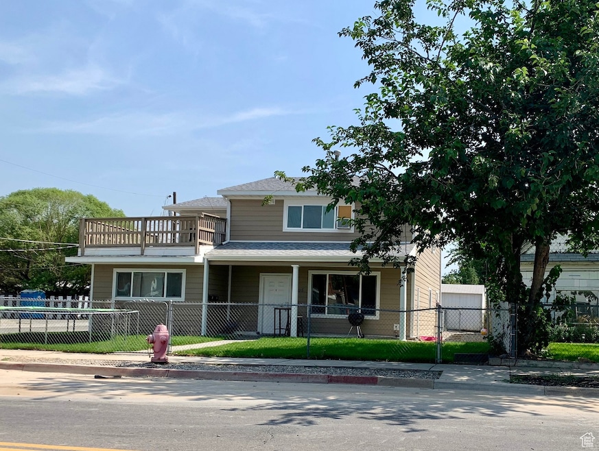 View of front of home with a balcony, a fenced front yard, covered porch, and roof with shingles