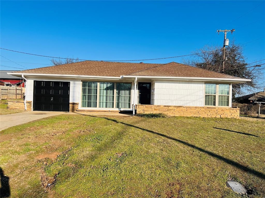 View of front of home with a front yard and a gara