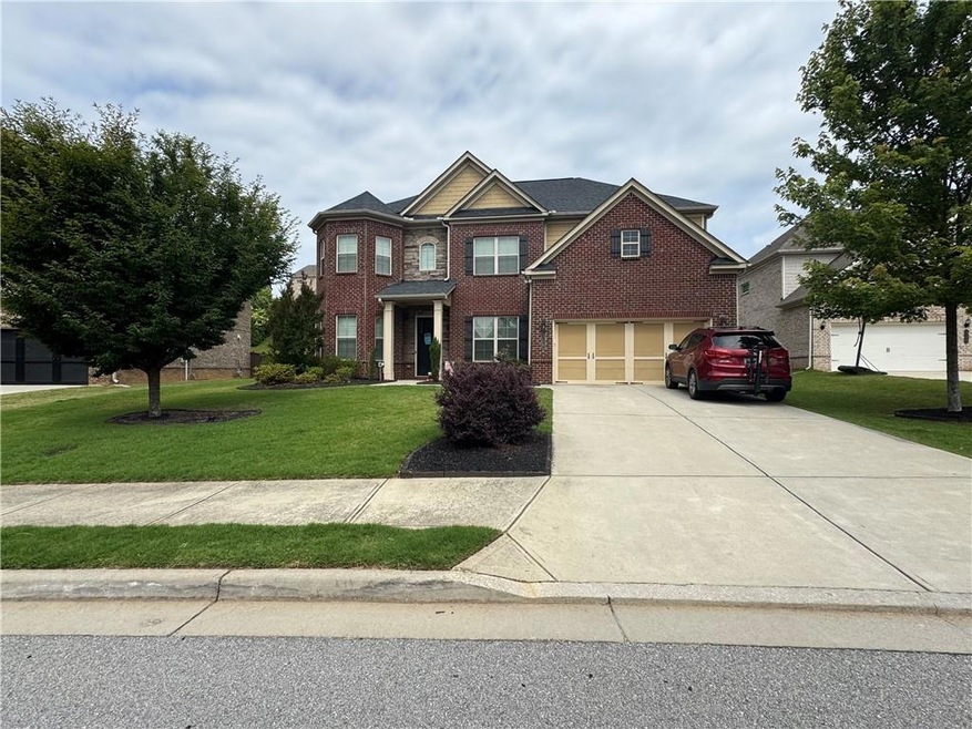 View of front facade featuring driveway, brick siding, a front yard, and a garage