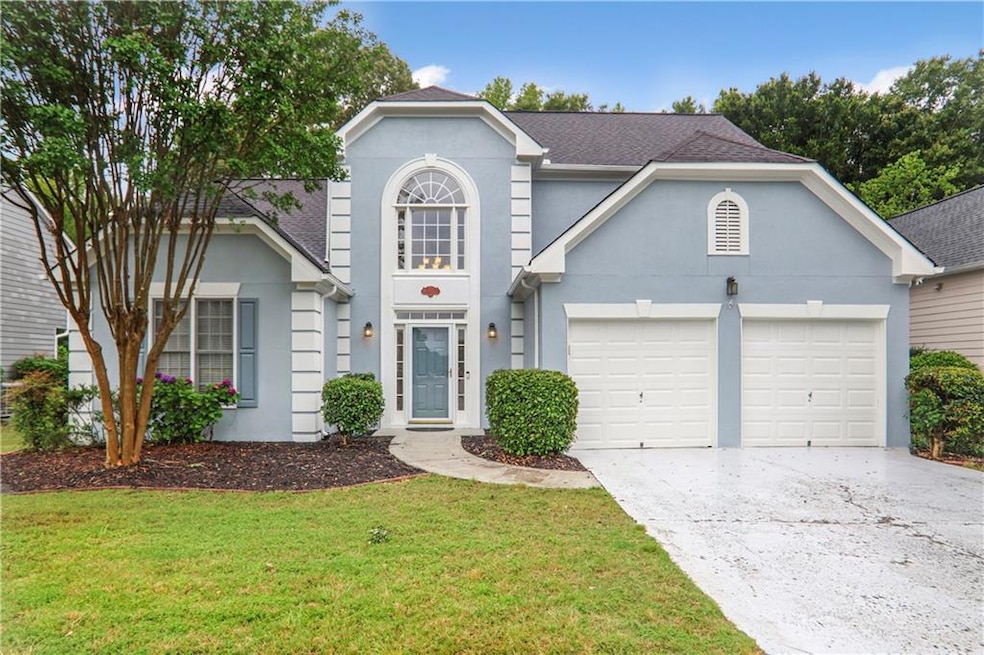 Traditional-style home with a garage, concrete driveway, stucco siding, a front lawn, and roof with shingles