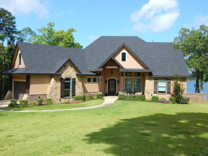 Craftsman house with stone siding, a front lawn, and roof with shingles