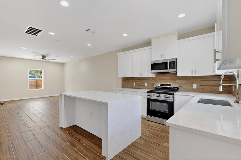 Kitchen featuring light stone countertops, appliances with stainless steel finishes, a center island, wood tiled floors, and recessed lighting