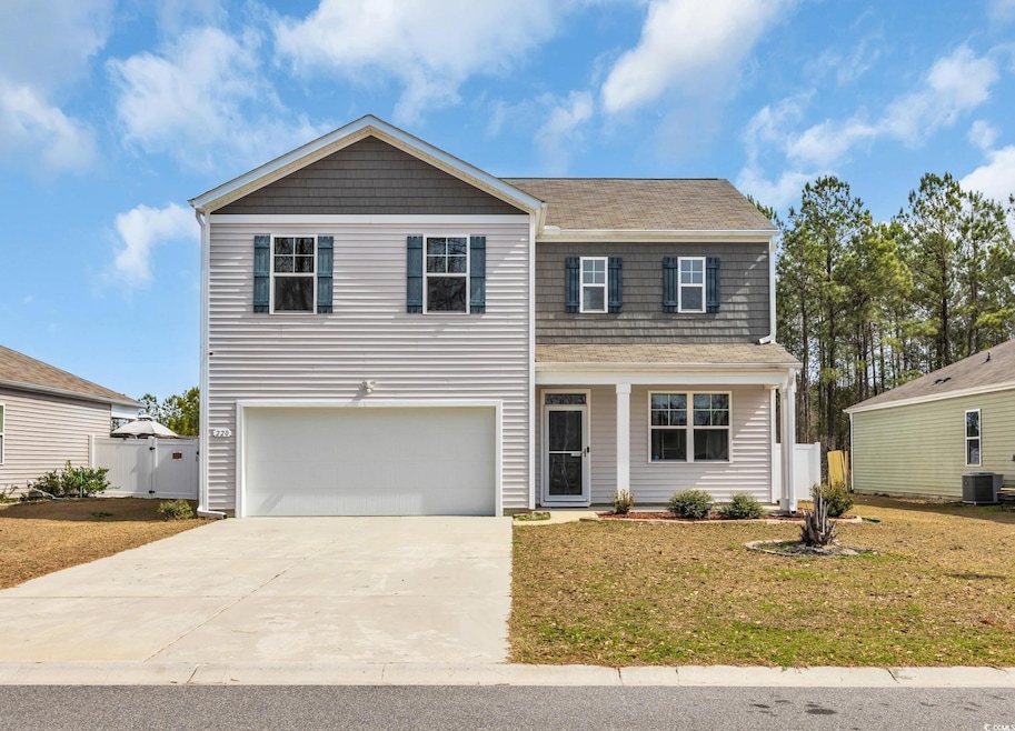Traditional-style house with a garage, central AC unit, concrete driveway, fence, and a front yard