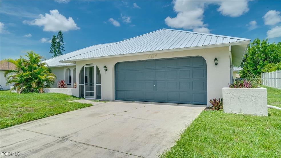 View of front of home featuring stucco siding, a metal roof, a front lawn, driveway, and a garage