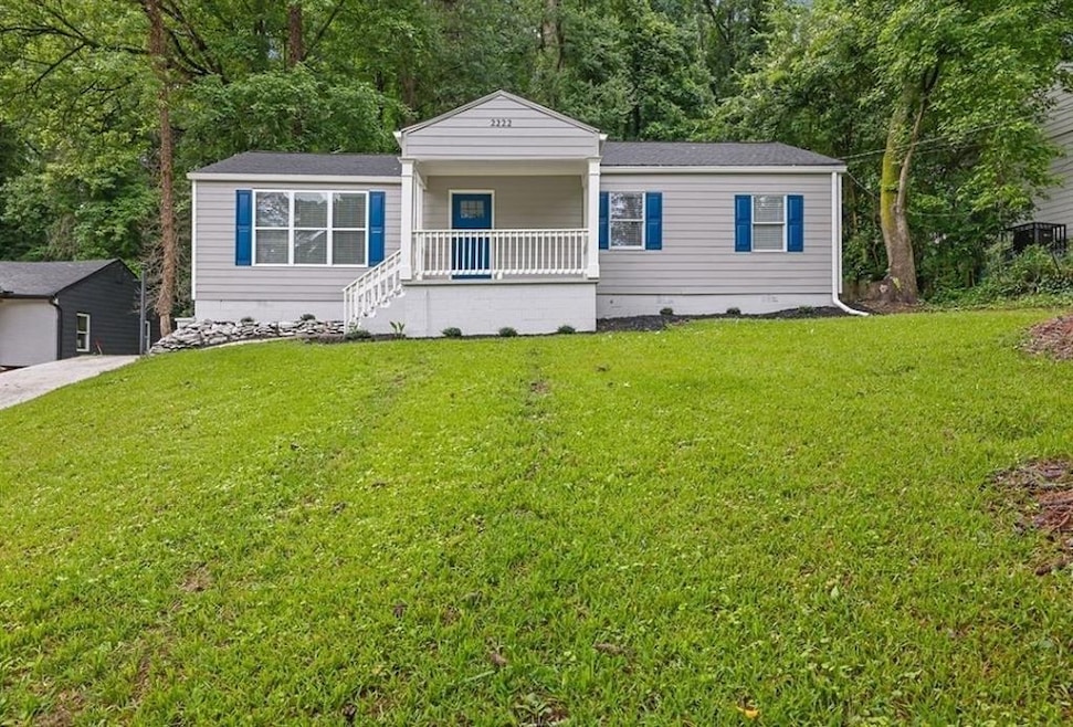 View of front of property with covered porch, a front lawn, and a shingled roof