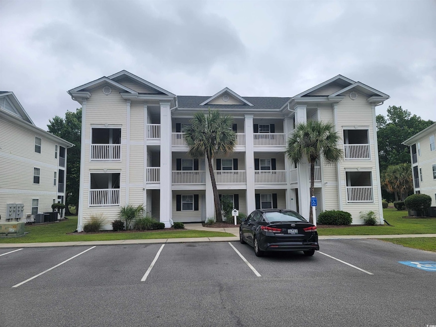 View of building exterior featuring uncovered parking and cooling unit