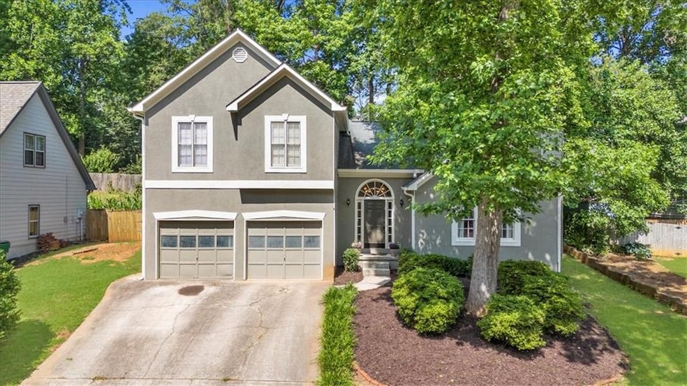 View of front of property featuring stucco siding, an attached garage, and driveway