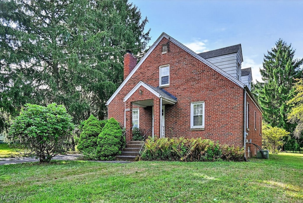 View of front of brick home with front & side yards & concrete driveway