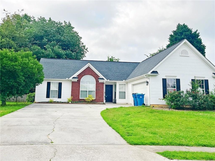 View of front of home featuring concrete driveway, a front yard, a garage, and roof with shingles