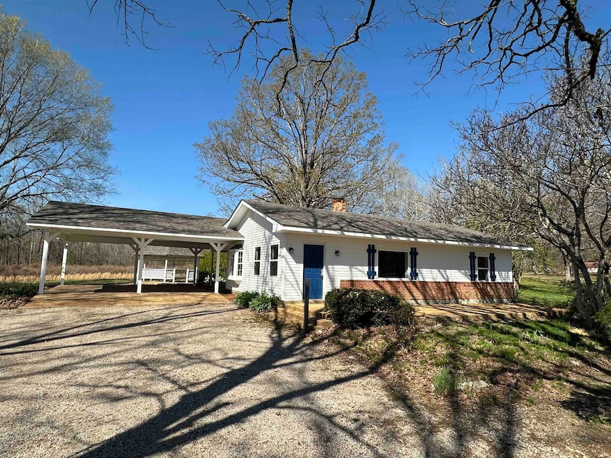 View of front of property featuring driveway, a chimney, and a carport
