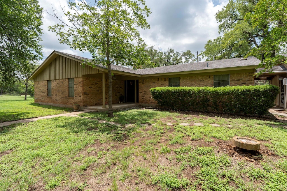 Back of house with brick siding, a lawn, and a pa