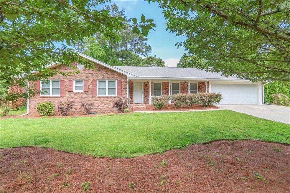 Ranch-style house with driveway, an attached garage, a front lawn, brick siding, and a porch