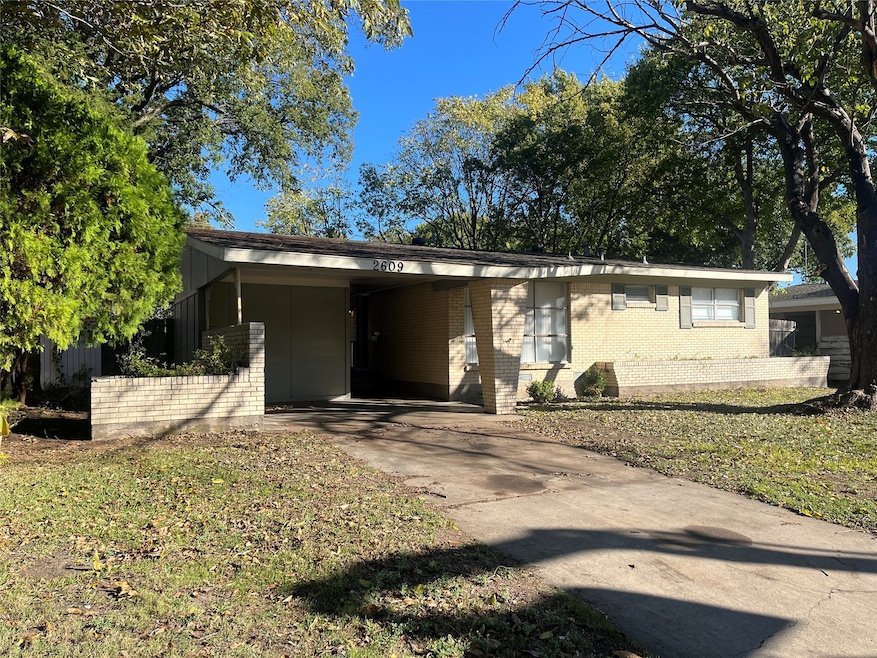 Ranch-style house featuring driveway, an attached carport, brick siding, and a front yard