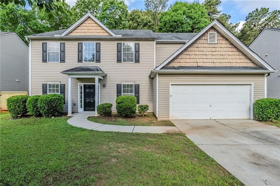 View of front of house featuring an attached garage, driveway, and a front yard