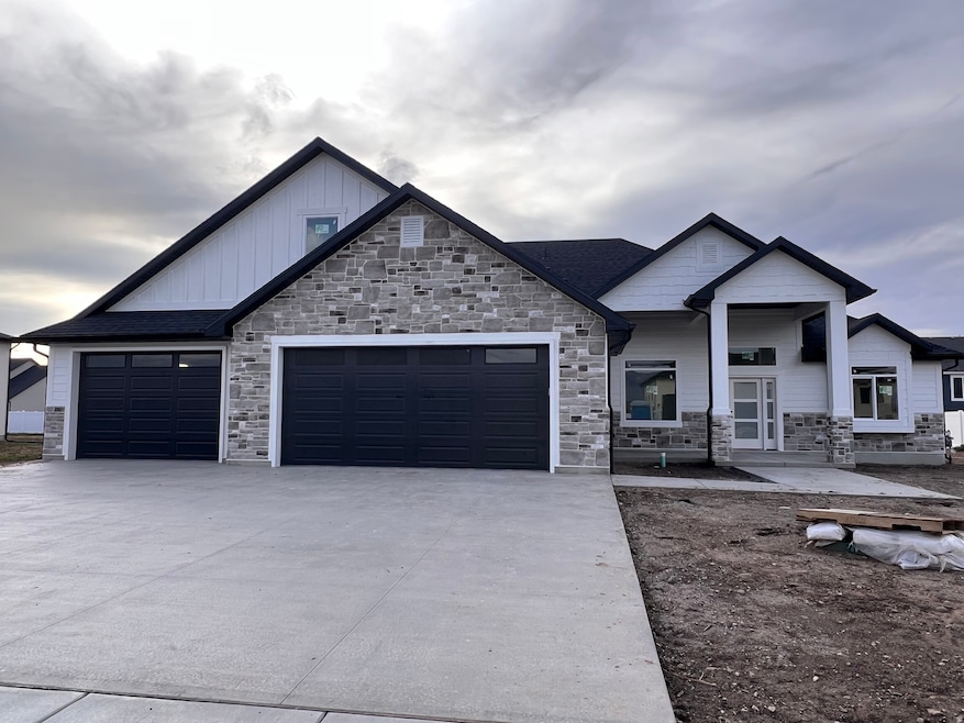View of front of property featuring covered porch, board and batten siding, stone siding, and driveway
