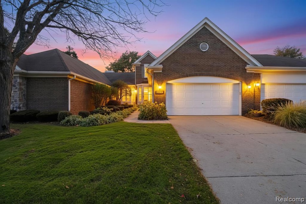 Traditional home featuring concrete driveway, brick siding, a lawn, and an attached garage