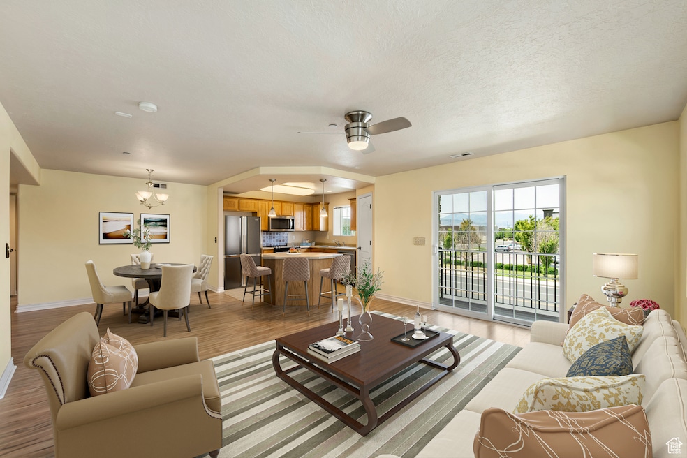 Living area featuring light wood-type flooring, a chandelier, and ceiling fan