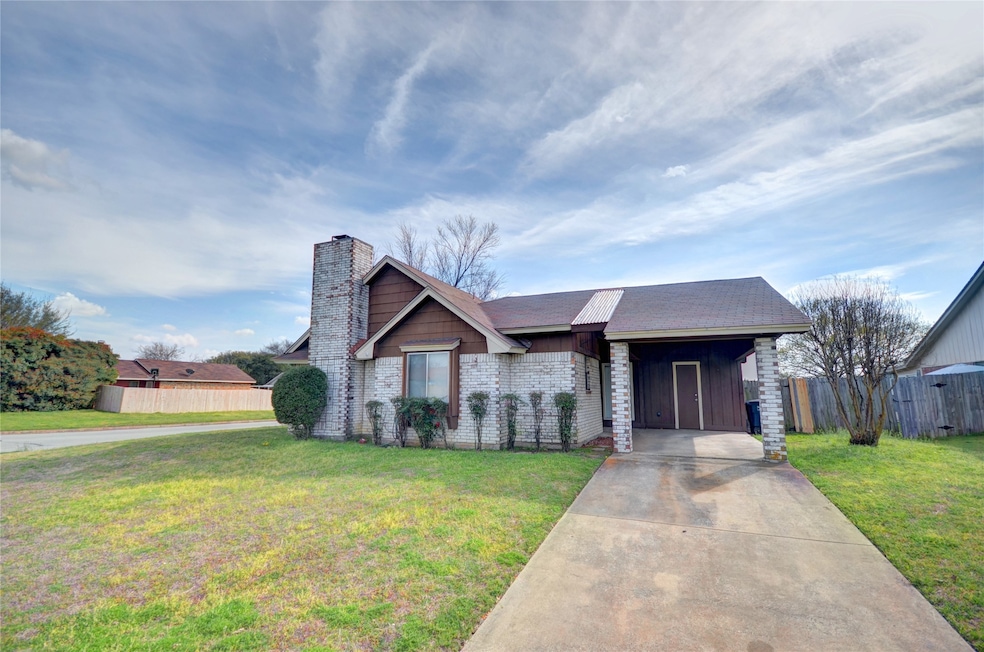 Single story home featuring a chimney, brick siding, concrete driveway, and a shingled roof