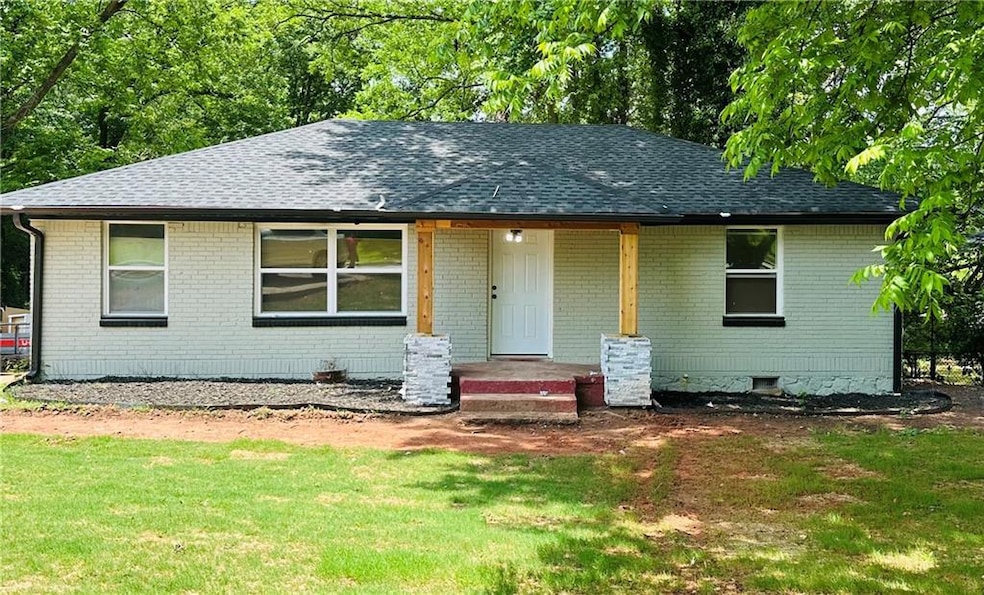 View of front of house featuring a shingled roof, brick siding, and a front yard