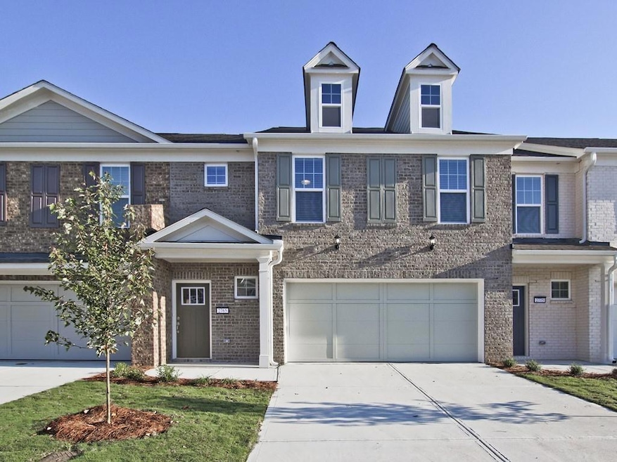 View of property featuring a garage, driveway, and brick siding