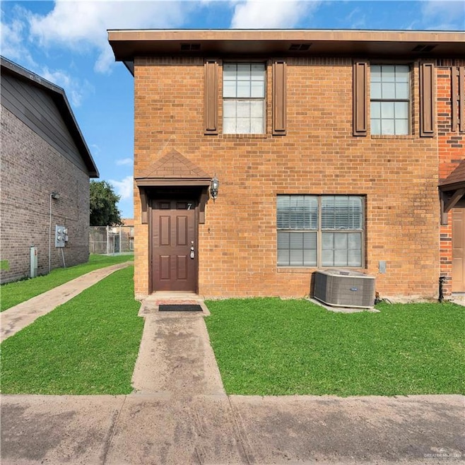 View of front facade featuring central AC, a front lawn, and brick siding