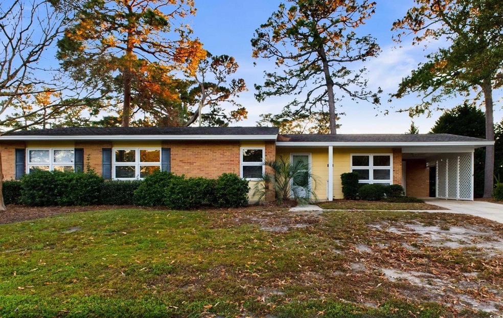 Ranch-style duplex featuring a carport and a front lawn