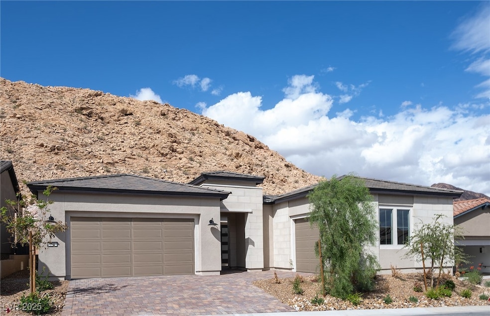 Prairie-style home with decorative driveway, an attached garage, a mountain view, and stucco siding