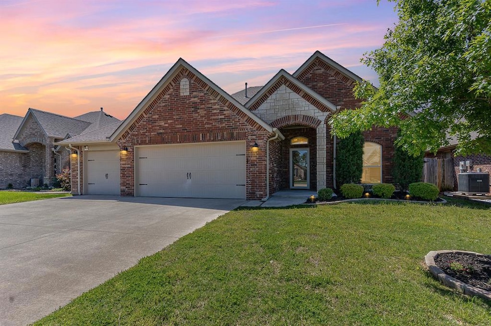 French country home featuring a garage, concrete driveway, and brick siding