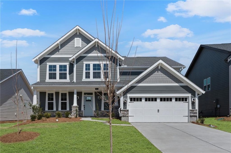 Craftsman-style house with stone siding, an attached garage, concrete driveway, and a front yard