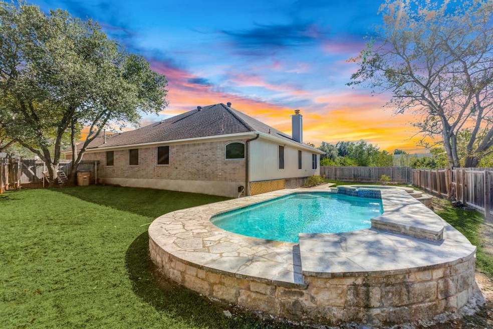 Pool at dusk with a fenced backyard, a pool with connected hot tub, and a patio area