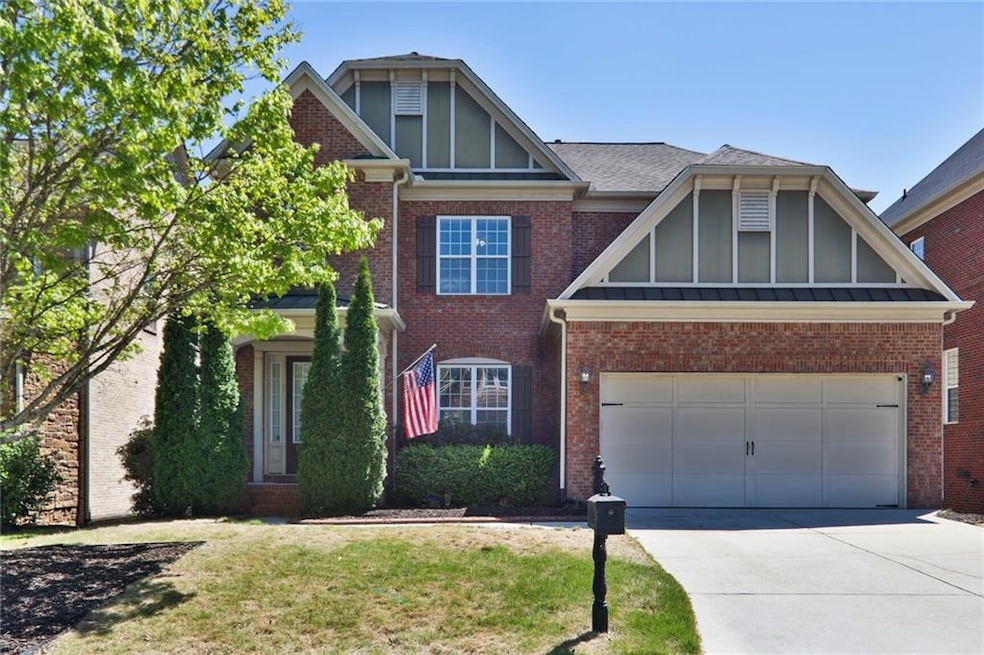 View of front of property with driveway, brick siding, an attached garage, board and batten siding, and a front yard