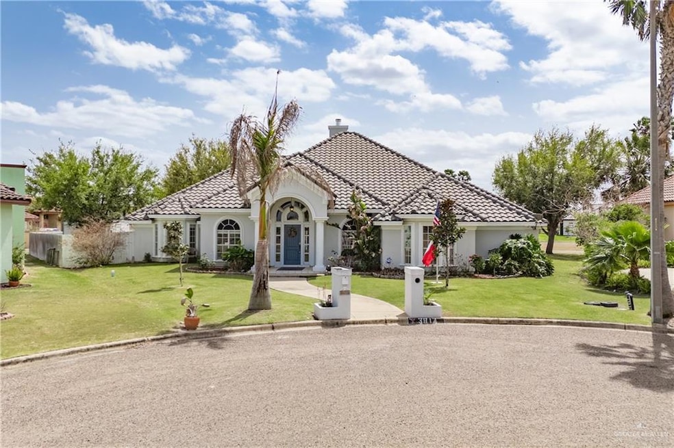 Mediterranean / spanish home with a front lawn, a tiled roof, a chimney, and stucco siding