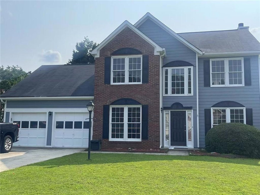 View of front of house featuring a garage, driveway, brick siding, a front lawn, and roof with shingles