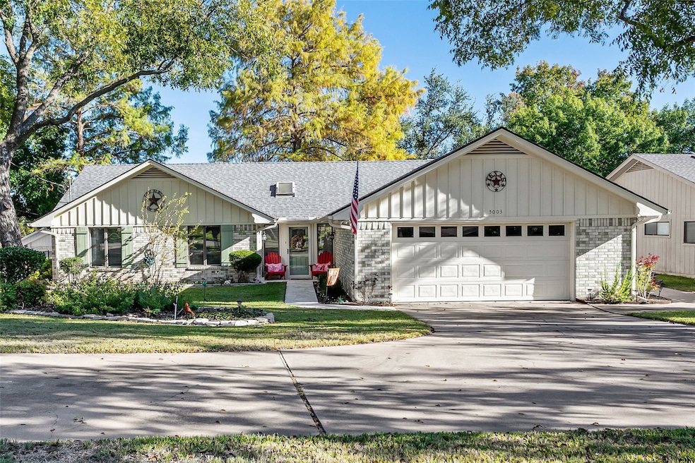 Ranch-style home with a shingled roof, board and batten siding, brick siding, and driveway