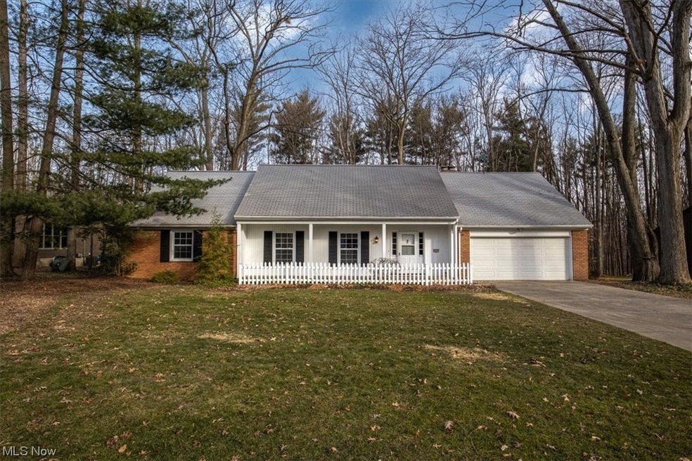 Ranch-style home with a front yard, a garage, and a porch